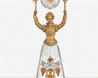 267
A German "Jungfrauenbecher" Maiden's Cup
19th Century
The gilt-bronze and glass figural maiden's cup in the form of a woman with a wide skirt holding a pivoting glass bowl above her head, with hand-painted enamel decorations and inscription reading "alles gluck dem brautpaare" [all the luck to the bride and groom]
11" H x 3.75" Dia.
Estimate: $500 - $700