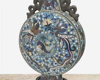 279
A Large Chinese Cloisonné Moonflask
First-quarter 20th Century
The enamel cloisonne moonflask with flat circular body, tapered cylindrical neck, and two scrolled handles raised on a flared foot with all-over polychrome dragon, fish, and foo dog motifs against a blue ground set atop an openwork carved wood stand
Overall: 17" H x 10" W x 6" D
Estimate: $1,000 - $1,500