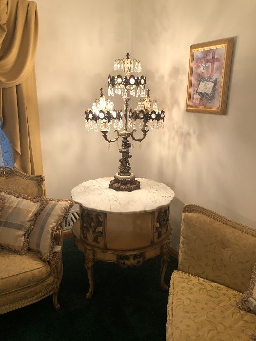 Unique brass lamp adorned with crystals and cherubs atop beautiful Italian-made end table with marble top.