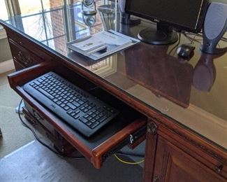Desk with glass top, tilt down keyboard drawer and lower file drawers.