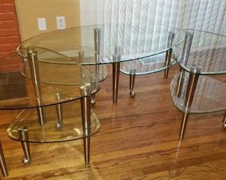 Glass Table Set: Cocktail Table & 2 Side Tables. Two tiered tables. 2nd tiers have wheels and tables swing out. More photos available upon request. Available for pre-sale. Please contact us at contactmvp@moorevaluepros.com for more information or to purchase. 