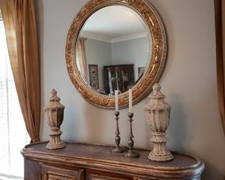 Silver and gold tone round mirror above side cabinet