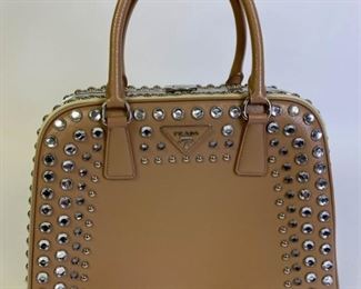 Lot	212	Prada Saffiano Lux Pyramid Two Tone Studded Purse	Authentic Prada tan and beige saffiano leather framed bag featuring faux crystal jewels with silver tone round studs. Prada logo triangle at top center, push lock closure at top, blush pink leather lining with two zip pockets and two slip pockets, made in Italy. Excellent condition. 12.5" l x 10" h x 5" w
