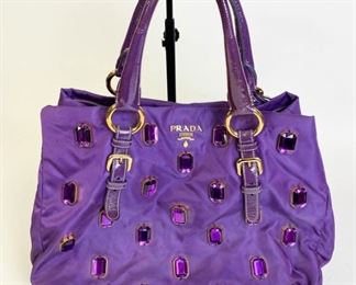 Lot	216	Prada Purple Tessuto Nylon Pietre Jeweled Tote	Purple Satin Prada Rhinestone Jeweled Purse, double handles with luggage tag, purple jewels are all intact, gold tone hardware, fabric lined with two interior zipper pockets, like new condition 16" L x 10" h x 7 D

