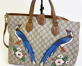 Lot	220	Gucci Embroidered Peacock Flower Tote Bag	Made in Italy. Part of the Gucci Garden Souvenir Collection, this tote Is embellished with hand-finished embroidered peacock and floral appliques. This Special design was created exclusively for Gucci. Made In soft Gg supreme, from a coated microfiber fabric with the Gg motif. Brown leather trim. Magnetic closure on the top, which is not lining up fully. Fully lined bag: one zipped main pocket and two patch pockets. Double Leather Handles With 4.5" Drop. Detachable And Adjustable Shoulder Strap With 19.5" Drop. 15" L x 11.5" h x 6" D Ink stains on interior of bag
