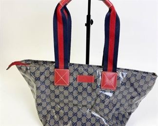 Lot	223	Gucci Tote with Red and Blue Handle	Oilcloth Gucci fabric bag with red zipper closure. Some transfer of Color from the red strap to both side of the purse, see photos 17" l x 9" w x 8" d
