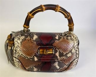 Lot	224	Gucci Python Snakeskin Purse	Python Gucci New Bamboo satchel with gold-tone hardware, single bamboo structured top handle featuring tassel charm, single detachable flat shoulder strap, tan canvas lining, dual pockets at interior wall; one with zip closure and bamboo turn-lock closure at front flap. Mirror included. Excellent condition. 11" l x 7" w x 4.5" d

