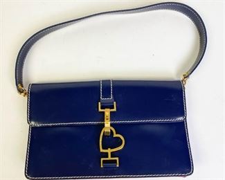 Lot	226	Moschino Blue Purse	Blue and red leather with gold tone heart latch. Red fabric lining with pocket. Some marks and dents in the leather and by latch. 9.5" l x 6" w x 1.5" d
