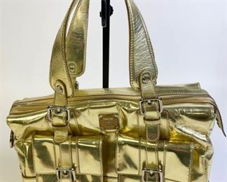 Lot	248	MCM Gold Handbag	Metallic gold exterior with double handles, two buckled outside pockets, silver fabric lined with lion logo, marked Made in Italy MCM Munchen, one zipper pocket, removable shoulder strap, 13"L x 5 1/2"W x 7"D
