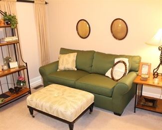 The family room has a sleeper sofa, fern motif ottoman and other furniture pieces.  