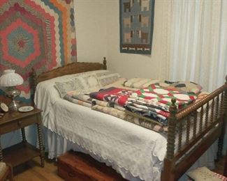 Antique quilts stacked on bed.