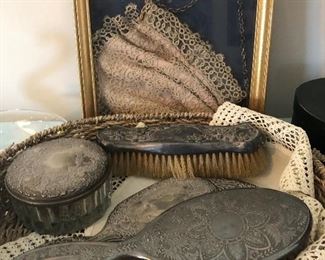 Combs, brushes, mirrors, and in the background a tatted purse, framed. 