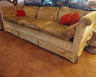 Enormous gold velvet sofa and orange accent pillows, slight feline customization...