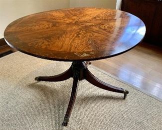 $2,400 - Georgian round inlay flame mahogany pedestal table.  Brass castors.   Wear consistent with age and use. 28.5"H x 48"D