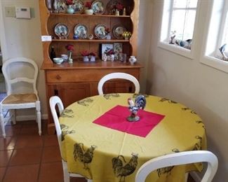 Farmhouse table has pine top and chicken motif on tablecloth. Maple hutch provides great storage
