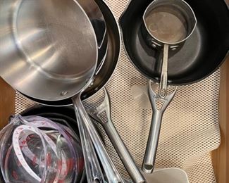 Assorted Measuring cups, Calphalon and All-Clad Cookware. 