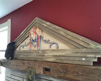 Large wooden decor over fireplace. Lady’s head is pottery. 