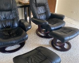 Set of 2 black, leather swivel chairs by Lane with matching ottomans. Measures 34”W x 34”D x 38”H