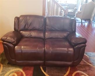 Dark brown leather love seat, area rug