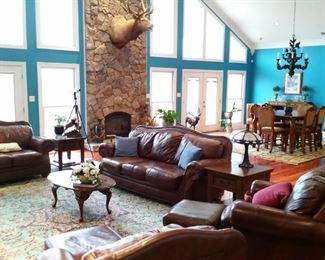 The living room features a leather sofa, love seat, and two chairs with ottomans.