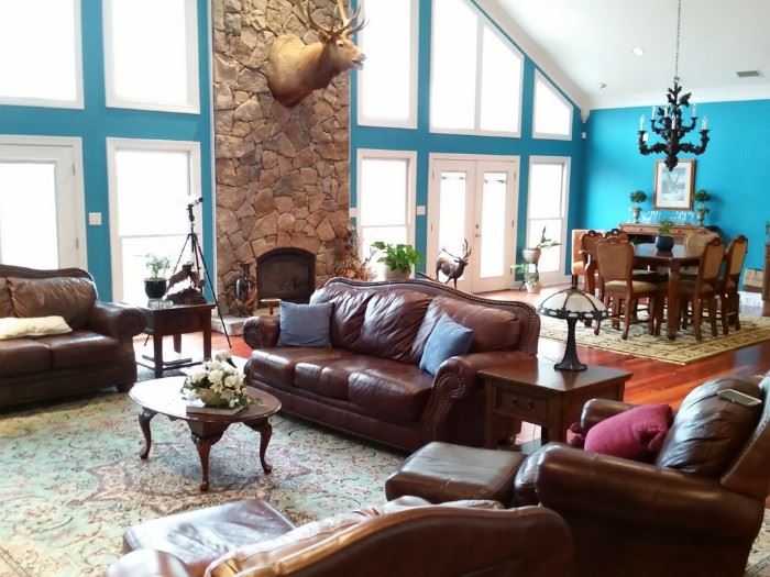 The living room features a leather sofa, love seat, and two chairs with ottomans.