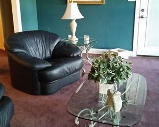 The second of two navy blue leather chairs, a glass top coffee table and second end table