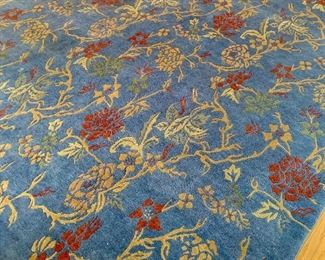 $1400 - Hand tufted multi-color Tibetan style rug; floral motif of gold, green and red on blue field; 11' 7" x 9' 1"  