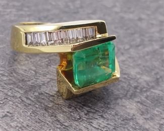 Before now very few have seen the color of tropical sea green like that similar to Emeralds from Columbia. This special ~5 ctw Columbian Emerald Cut Emerald is one such gem. The Emerald is set on the long side and nestled between 2.20 Carats of intensely bright channel set diamond baguettes and artfully molded into a modernistic and sophisticated look with 18k Yellow Gold. You may see something similar but never...never see this color and style again.