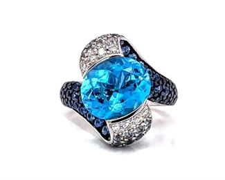 Truly one-of-a-kind! Feast your eyes on this couture statement ring, with a suspended Betty Davis Eye Blue Topaz and graduating Diamonds, Natural Blue Sapphires, and Tanzanite down each water wave side design. The whole ring is gathered together with solid 18k white gold and will no doubt make many eyes blink!