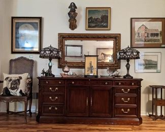 Mahogany credenza, by Sligh, pair of stained glass double bulb table lamps, original porcelain man on donkey "Don Quixote" Lo Scriolo, signed H. Columbo, antique wood/gilt wall mirror, taxidermied birds, on branches, vintage wooden smoking stand, faux wood wall pirate and three pieces of original framed artwork and one of a pair of vintage French walnut/cane armchairs.