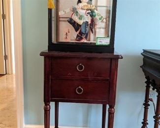 Two-drawer side table, with Japanese doll in glass case. 