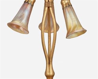 4
A Tiffany Studios Three-Light Lily Table Lamp
Circa 1902-1919; New York, NY
Each shade signed: L.C.T. / Favrile; Base signed: Tiffany Studios / New York / 319
The gilt-bronze base with a ribbed foot and tri-form stem issuing a drop cluster of three gold iridescent Favrile glass "Blossom" shades, electrified
12.75" H x 11" Dia.
Estimate: $2,000 - $3,000