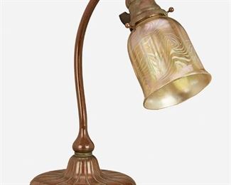 5
A Tiffany Studios Table Lamp
Circa 1903; New York, NY
Shade signed: L.C.T.; Base signed: Tiffany Studios / New York / [T.G.D.Co. monogram] / 28609
The gold iridescent Favrile glass damascene shade with swirled motif and shades of blue on a patinated bronze gooseneck base with curving stem and circular foot with incised lotus motif, electrified
14.25" H x 6.5" W x 12.5" D
Estimate: $2,000 - $3,000