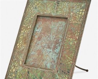 18
A Tiffany Studios Bronze "Pine Needle" Frame
Circa 1902-1919; New York, NY
Signed: Tiffany Studios / New York / 947
The rectangular verdigris patinated bronze frame with green glass, pine needle motif bronze overlay, and beaded border enclosing a rectangular opening
Overall: 9.5" H x 8" W x 6" D; Opening: 5.375" H x 3.875" W
Estimate: $1,000 - $1,500