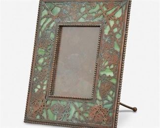 19
A Tiffany Studios "Grape Vine" Bronze Picture Frame
Circa 1902-1919; New York, NY
Signed: Tiffany Studios / New York
The rectangular verdigris patinated bronze "Grape Vine" frame with green mottled glass and bronze overlay enclosing a rectangular opening
8.75" H x 7.25" W x 4.5" D; Opening: 4.75" H x 3.25" W
Estimate: $600 - $800