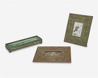 20
Three Tiffany Studios Desk Accessories
Circa 1902-1919
Each signed: Tiffany Studios / New York
Each verdigris patinated bronze, comprising a rectangular picture frame with green rippled glass and foliate motif bronze overlay, a calendar frame with green mottled glass and foliate motif bronze overlay, and a "Grape Vine" pen tray with green mottled glass and bronze overlay, 3 pieces
Largest: 6.375" H x 7.5" W; Smallest: 1.5" H x 8.5" W x 3" D
Estimate: $400 - $600