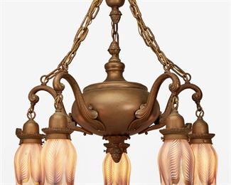 42
A Gilt-Bronze Chandelier With Five Quezal Art Glass Shades
First-quarter 20th Century
Each shade signed: Quezal
The five-light gilt-bronze chandelier with bulbous body, acorn finials, canopy, and suspended chain link harness issuing five scrolled arms terminating in white and blue Quezal floriform glass shades with pulled feather motif and iridescent gold transition, electrified
24" H x 22" Dia.
Estimate: $1,500 - $2,000