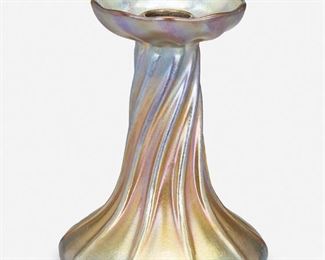79
A L.C. Tiffany Favrile Glass Candlestick
Circa 1892-1919; New York, NY
Signed: L.C.T.
The gold iridescent Favrile glass candlestick shaded to blue with swirled base terminating in a bobeche with metal liner
5.125" H x 3.75" Dia.
Estimate: $400 - $600