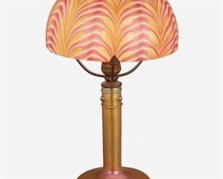 94
An Iridescent Art Glass Boudoir Lamp
First-quarter 20th Century
The Tiffany-style iridescent glass shade with cranberry and orange pulled feather motif atop three patinated bronze arms with leaf-style terminals on a Stueben Aurene-style iridescent gold glass base with straight column, circular foot, and prunt decorations, electrified
Overall: 16" H x 9" Dia.
Estimate: $400 - $600