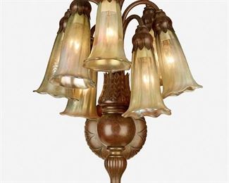95
A Tiffany-Style Lily Wall Sconce
20th Century
One shade signed: Lundberg Studios / 2002
The patinated bronze lily wall sconce with ball-form base and shaped spindle issuing a drop cluster of seven lights, each with opalescent art glass floriform shades, joined with a bracket arm to an engraved back plate with bead trim, electrified
14" H x 11.75" W x 9.5" D
Estimate: $500 - $700