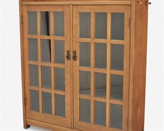 114
A L. & J.G. Stickley Double-Door Bookcase, No. 645
Circa 1906-1912; Fayetteville, NY
Label: L. & J.G. Stickley Handcraft
The original finish oak double-door bookcase with raised back panel over keyed mortise and tenon slab sides and two twelve-lite glazed mullion doors with rectangular panels, each finished with a hammered copper drop handle and lockplate, enclosing a fitted interior with three stationary shelves raised overall on four bracket feet
55" H x 52" W x 12" D
Estimate: $2,500 - $3,500