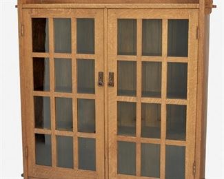 115
A L. & J.G. Stickley Double-Door Bookcase, No. 645
Circa 1912-1917; Fayetteville, NY
Label: The Work of L. & J.G. Stickley
The original finish oak double-door bookcase with raised back panel over keyed mortise and tenon slab sides and two twelve-lite glazed mullion doors with rectangular panels, each finished with a hammered copper drop handle and lockplate, enclosing a fitted interior with three stationary shelves raised overall on four bracket feet
55" H x 52" W x 12" D
Estimate: $2,500 - $3,500