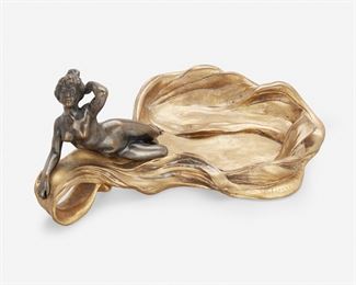164
An Art Nouveau Gilt-Bronze Figural Tray
Late 19th/early 20th Century
Signed: Lelievre
Possibly Eugene Lelievre, with a gilt-bronze free-form shaped tray and looped handle surmounted by a patinated bronze figural nude
3.375" H x 8.5" W x 5.5" D
Estimate: $300 - $500