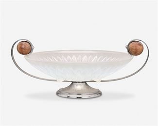 208
An Art Deco Art Glass Centerpiece
Second-quarter 20th Century
Appears unsigned
Likely Sabino, the blue-hued semi-transparent opalescent glass dish with cut floral motif raised on a silvered metal foot and fitted with two scrolled silvered metal handles with wooden ball details
6" H x 15" W x 11.875" D
Estimate: $400 - $600
