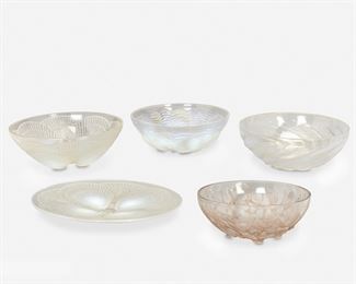 211
Five René Lalique Glass Table Items
Circa 1921-1932
Each signed: R. Lalique; Three further marked: France
Comprising one "Coquilles" platter, model no. 3009, with opalescent overlapping shell design to reverse, one "Coquilles" bowl, model no. 3200, with opalescent overlapping shell design to reverse, one "Dauphins" bowl, model no. 10-384, in opalescent glass depicting fish swimming among stylized waves, one "Poissons" bowl, model no. 3212, in opalescent glass with a spiral of sardines radiating around a stylized field of bubbles at the center, and one "Gui" bowl, model no. 3223, with brown mistletoe motif, 5 pieces
Largest: 1.5" H x 11.75" Dia.
Estimate: $700 - $900
