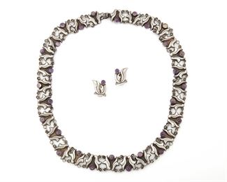273
A Horacio De La Parra Two Piece Jewelry Set
Necklace: Appears unsigned; Stamped: Mexico / Silver <br /> Earrings: Stamped: "Parra" for Horacio de la Parra; Further stamped: Hecho en Mexico / 925
Comprising a long foliated panel link necklace set with cabochon amethysts and screw-backed earrings, 3 pieces
Necklace: 30" L x 0.75" H; Earrings: 0.75" H x 0.75" W
Estimate: $400 - $600