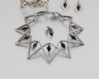 276
A Suite Of Antonio Pineda Silver And Obsidian Jewelry
1953-1979; Taxco, Mexico
Crown mark for Antonio Pineda; Eagle 17; Each further stamped: Hecho en Mexico / 970 / Silver
Comprising a diamond-shaped collar necklace with faceted diamond-shaped obsidian (14" L x 2.125" H) with matching bracelet (6.5" L x 1" H), a pair of screw-back earrings (2" H), and a ring (5.5), 5 pieces
239.0 grams
Estimate: $2,000 - $3,000