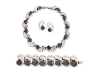 281
An Assembled Set Of Antonio Pineda Silver And Onyx Jewelry
1953-1979; Taxco, Mexico
Crown mark for Antonio Pineda; Further stamped: Eagle 17 / [indistict eagle]; Each variously stamped: Sterling / Mexico / Silver / YY439 / Hecho en Mexico / Made in Mexico / 518
A necklace, bracelet, and post back earrings comprised of silver wave segments alternating with round onyx, 4 pieces
Necklace: 15" L x 0.75" H; Bracelet: 6.75" L x 1.25" H; Earrings: 1.10" L x 0.75" W
220.0 grams
Estimate: $1,500 - $2,500