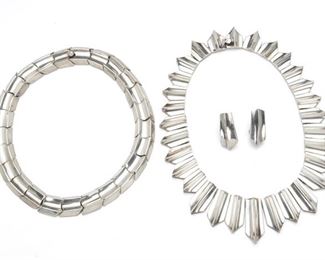 290
A Group Of Antonio Pineda Silver Jewelry
1953-1979; Taxco, Mexico
Crown mark for Antonio Pineda; Further stamped: Eagle 17 / [indistinct eagle]; Each variously stamped: Silver / Hecho en Mexico / 970 / YY591
Comprising a collar necklace design with pointed rays (15.5" L x 1.325" H) and with matching screw-back ear clips (1.25" H x .625" W), and a geometric link necklace (13.5" L x .75" H), 4 pieces
Necklaces: 15" L x 1.50" H & 14" L x 0.35" H; Earrings: 1.20" H x 0.50" W
290.0 grams
Estimate: $1,000 - $1,500