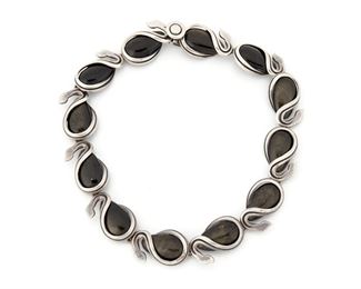 294
An Antonio Pineda Silver And Obsidian Necklace
1953-1979; Taxco, Mexico
Crown mark for Antonio Pineda; Further stamped: Eagle 17 / Hecho en Mexico / Silver / 970
Teardrop shaped obsidian link necklace wrapped in stylized silver snakes
15.50" long
112.0 grams
Estimate: $800 - $1,200